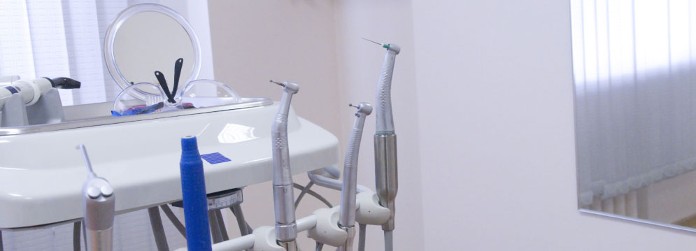 A photograph of a dental office interior with a sink, chair, and mirror, set against a blurred background.