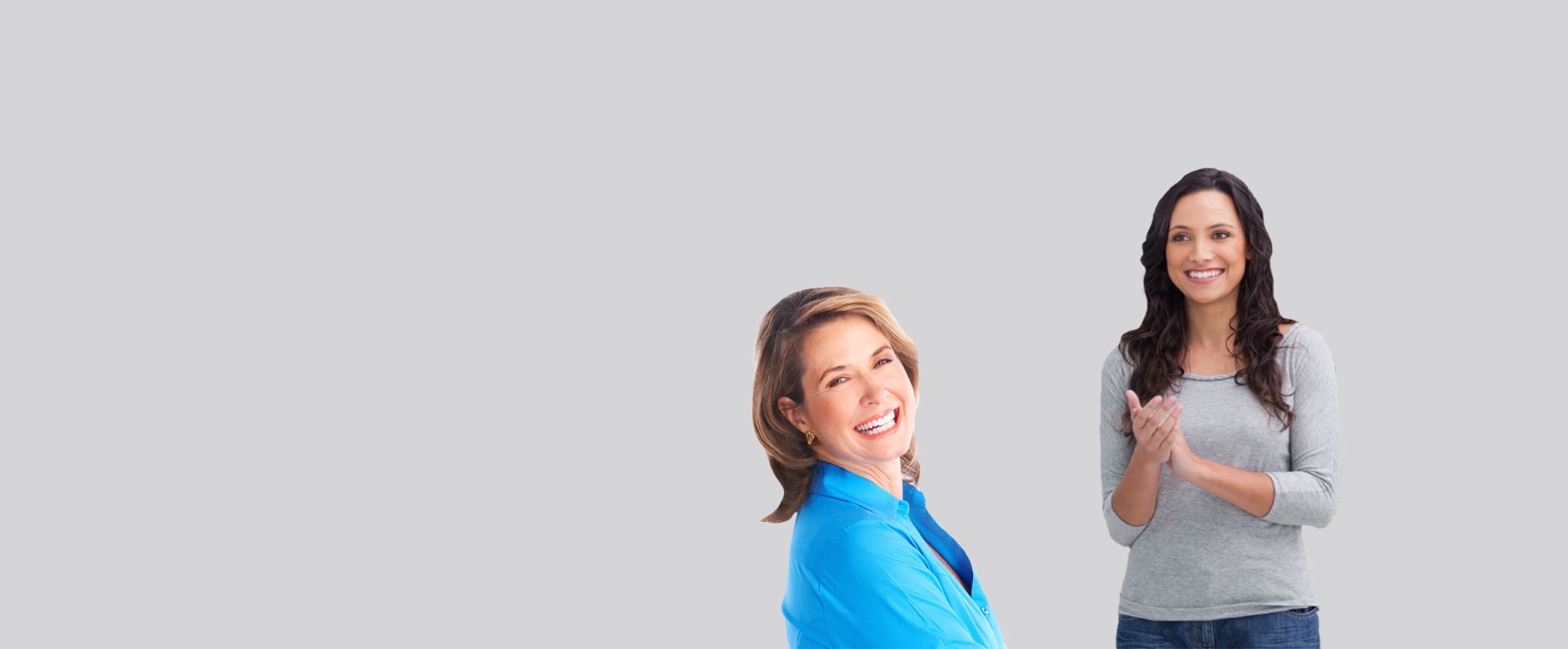 The image shows two individuals posing together with a backdrop  one person appears to be a woman standing behind another person, who seems to be a man, both smiling and looking directly at the camera.