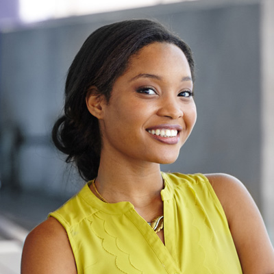 A woman with a radiant smile poses against a blurred background.